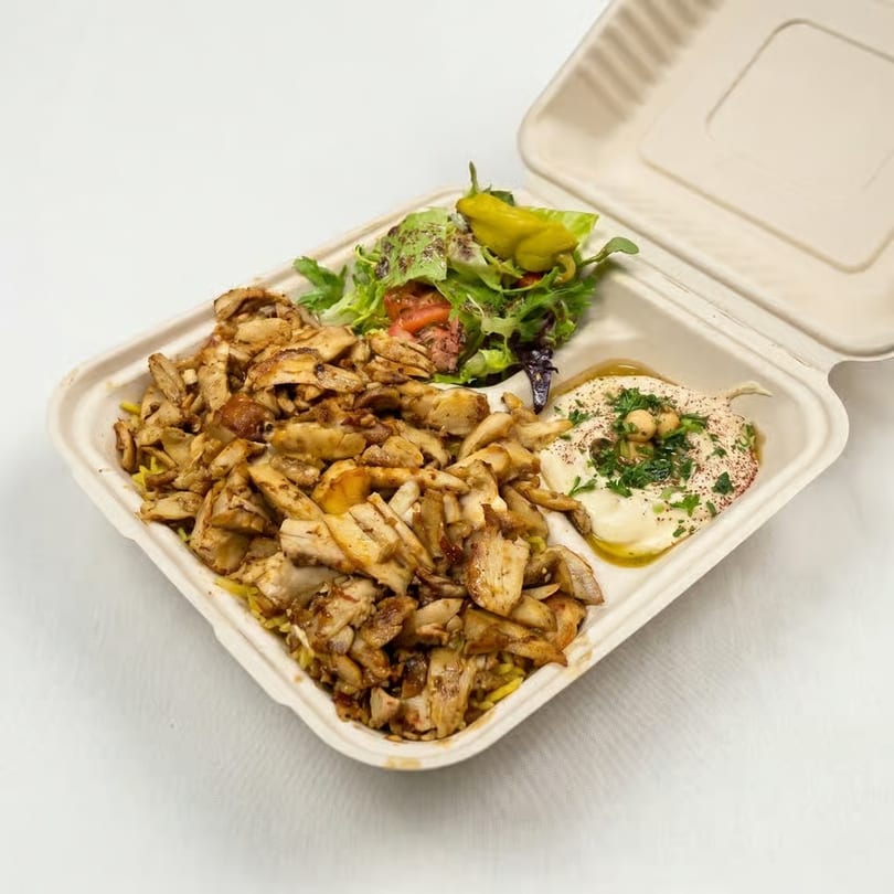 Chicken shawarma plate with rice, salad, hummus, and a pepper in a takeout container.