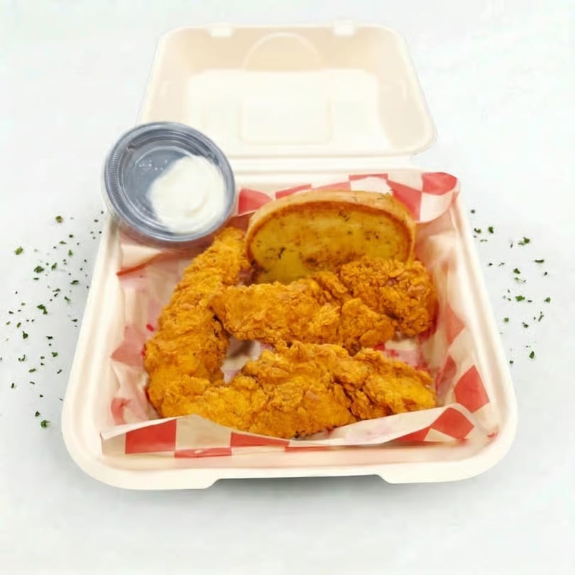 Crispy fried chicken tenders, garlic bread, and dipping sauce in a takeout container.